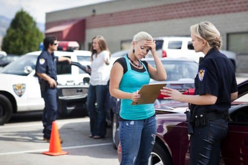 A woman talking to a police officer after a car accident.