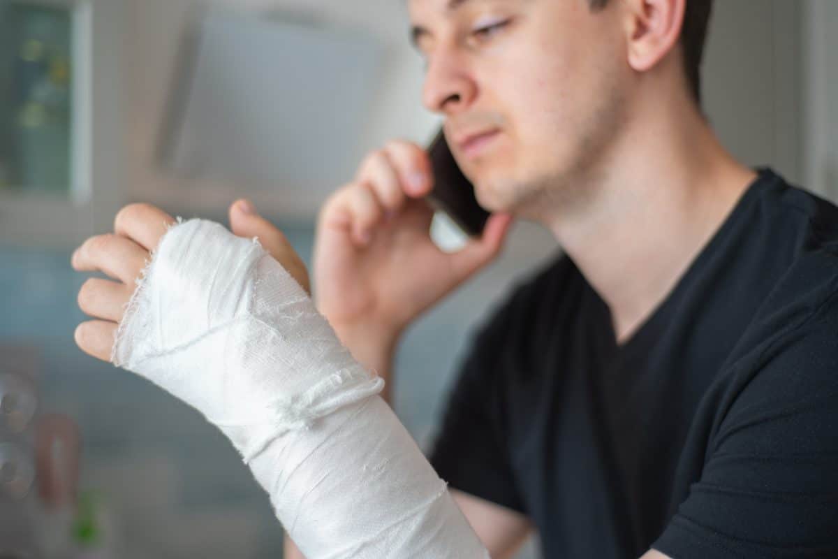 A man with a broken arm on the phone with his personal injury lawyer.
